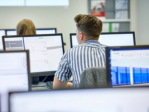 Studierende sitzen vor Computern in Lernraum